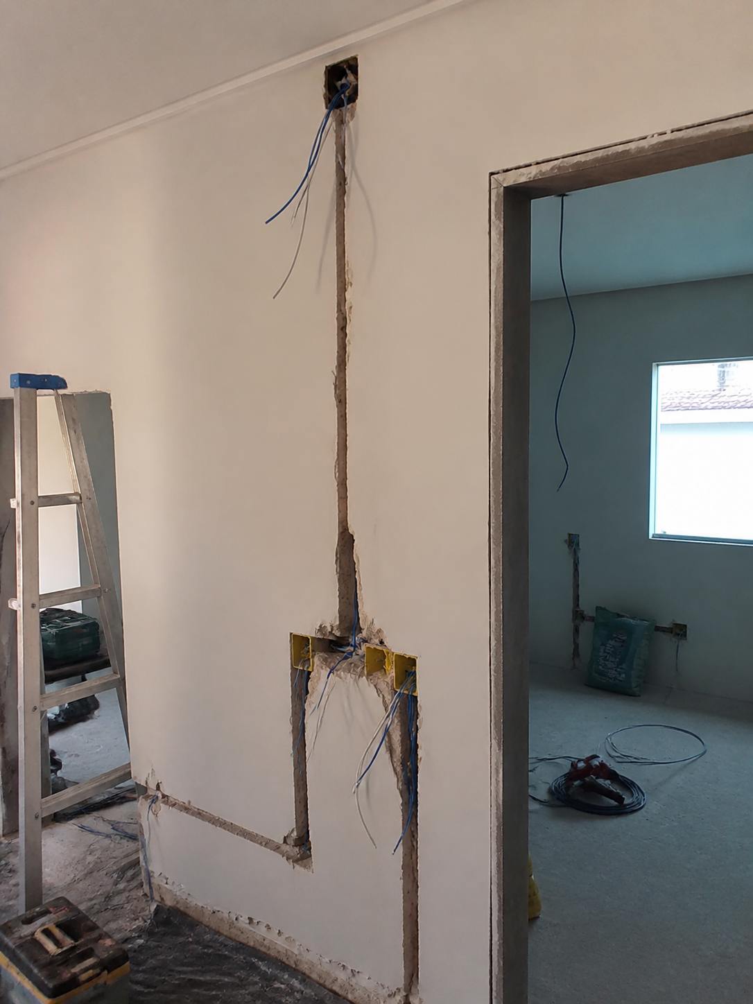 Instalação elétrica residencial com conduítes e fios aparentes durante obra