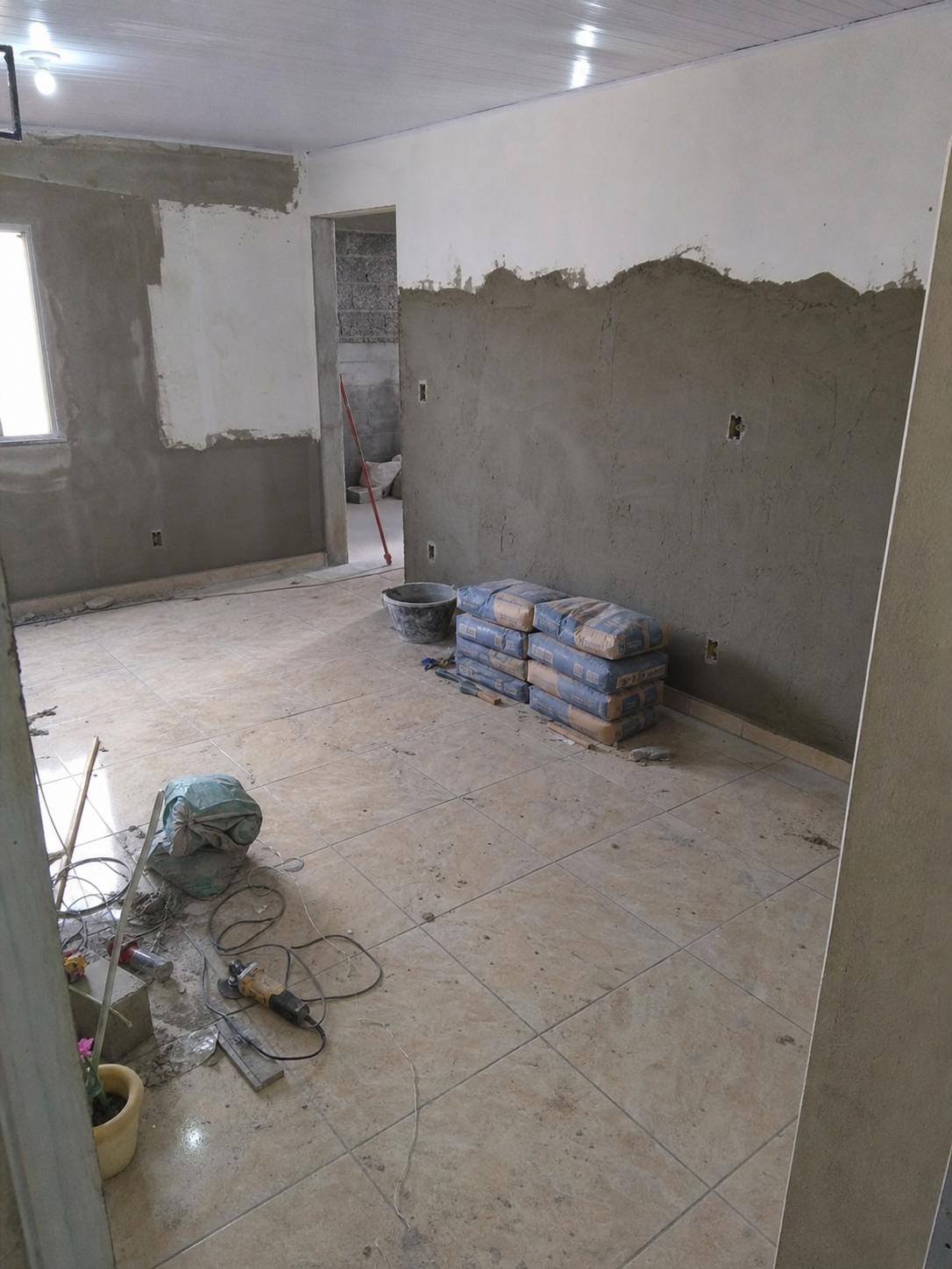 Ambiente residencial em reforma com argamassa, ferramentas e piso em obra